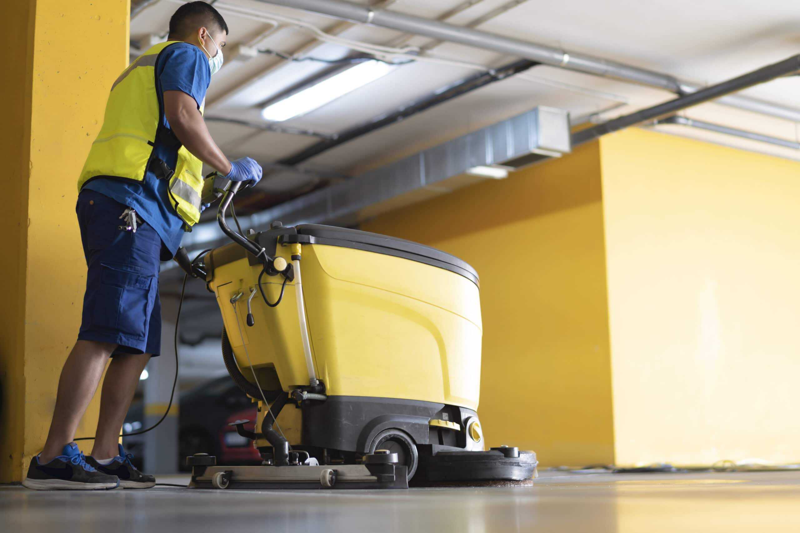 Mitarbeiter reinigt den Garagenboden mit einer modernen Reinigungsmaschine