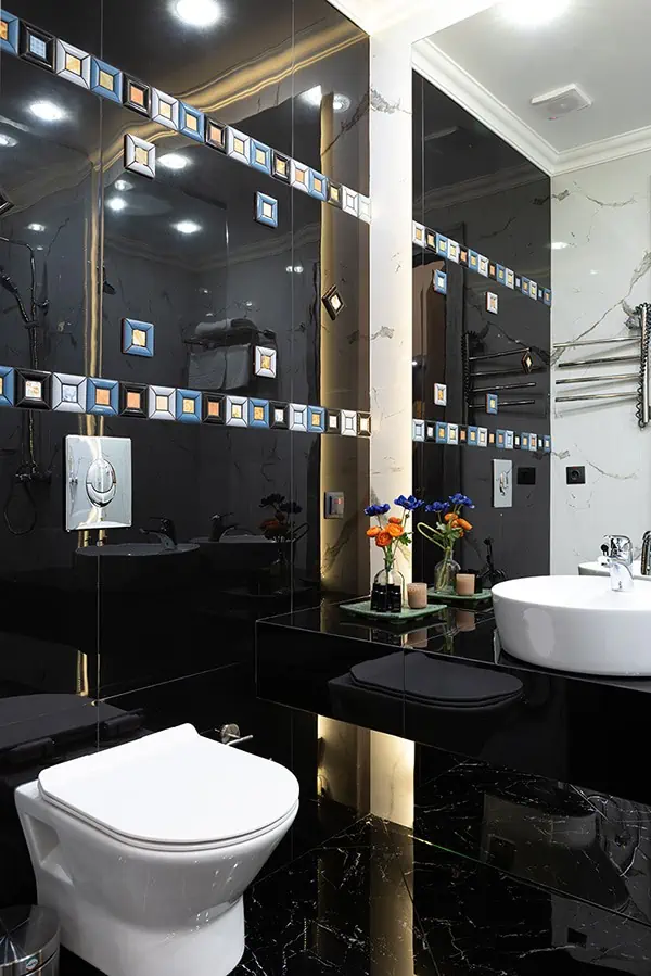 Modernes Badezimmer mit schwarzen Fliesen und goldenen Akzenten.
