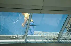 Ein Fensterreiniger steht auf dem Dach und reinigt die Fenster