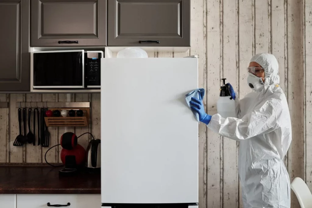 Eine Reinigungskraft reinigt einen Kühlschrank