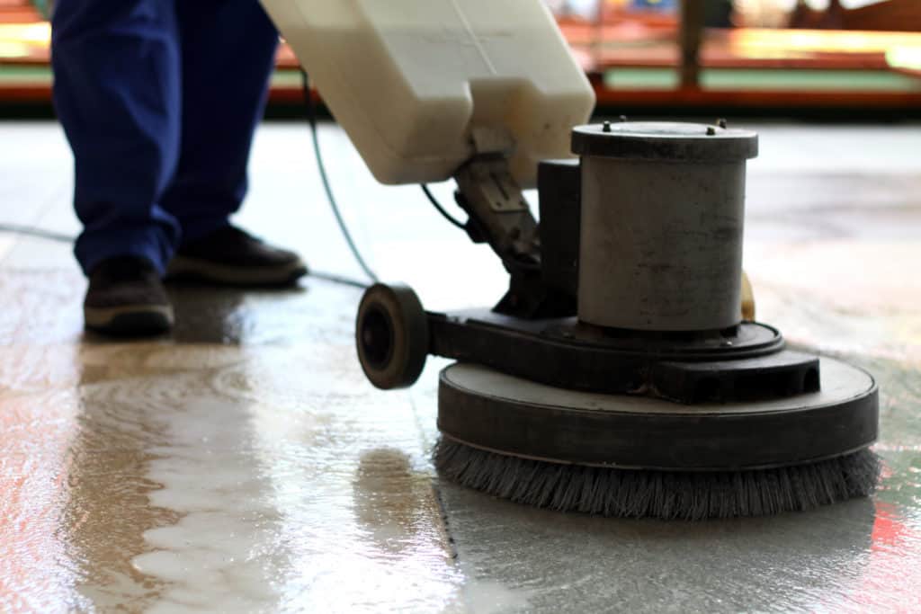 Ein Mitarbeiter einer Reinigungsfirma reinigt den Boden mit einer Einscheibenmaschine